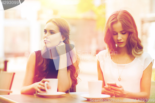 Image of women with smartphones and coffee at outdoor cafe