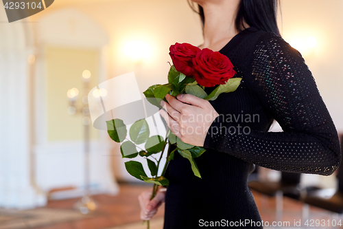 Image of woman with red roses at funeral in church