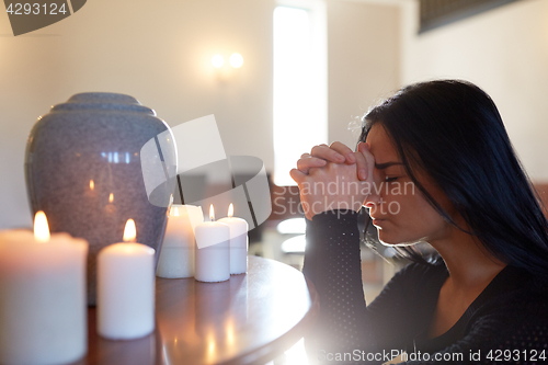 Image of sad woman with funerary urn praying at church