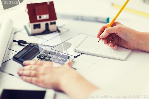 Image of close up of hand on blueprint writing to notebook