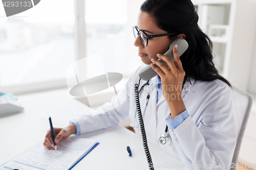 Image of doctor with clipboard calling on phone at hospital