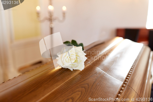 Image of white rose flower on wooden coffin in church