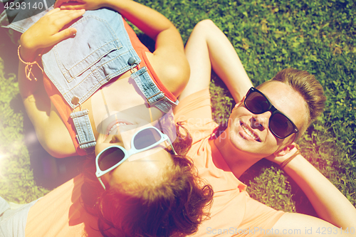 Image of happy teenage couple lying on grass at summer