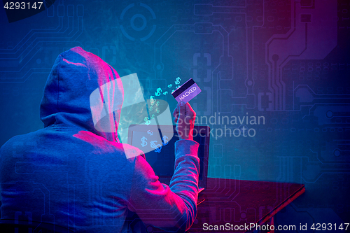 Image of Hooded computer hacker stealing information with laptop