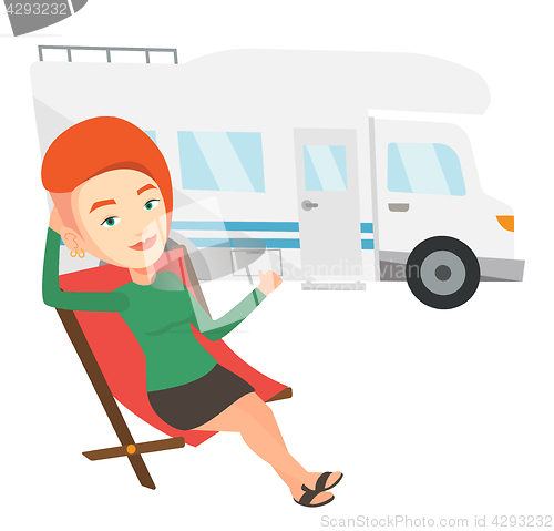 Image of Woman sitting in chair in front of camper van.