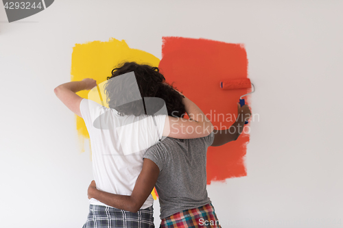 Image of multiethnic couple painting interior wall