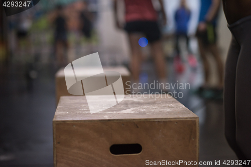 Image of black woman is performing box jumps at gym