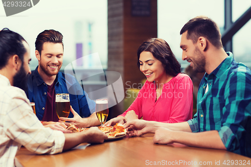 Image of friends eating pizza with beer at restaurant