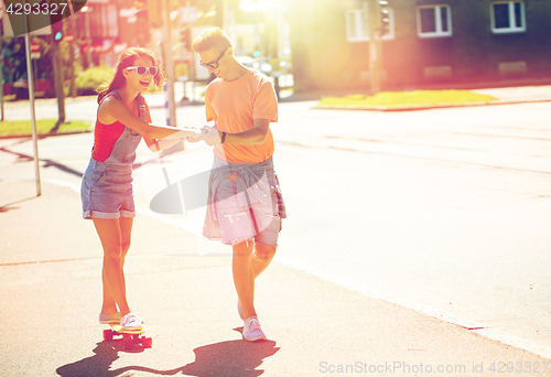 Image of teenage couple riding skateboards on city street