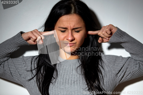 Image of unhappy woman closing ears by fingers