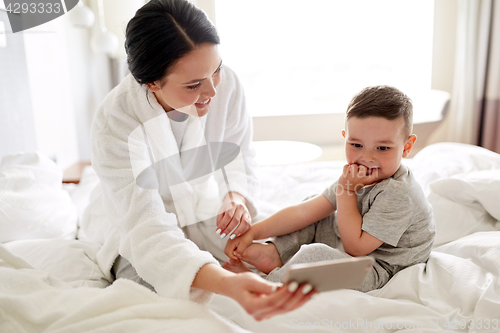 Image of mother and son with smartphone in bed at hotel