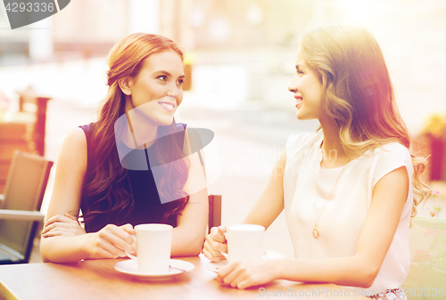 Image of smiling young women with coffee cups at cafe