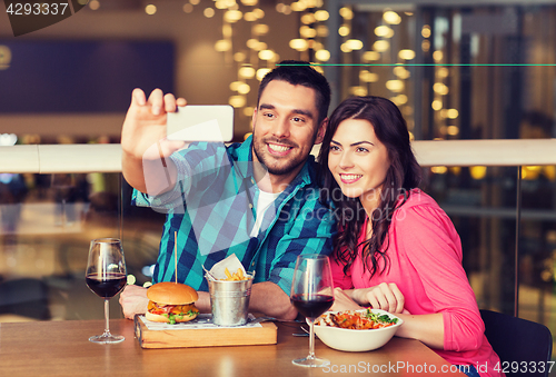 Image of couple taking selfie by smartphone at restaurant