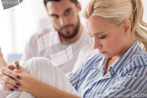 Image of unhappy couple having conflict in bed at home