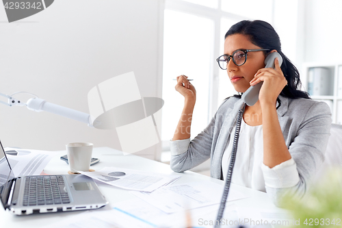 Image of businesswoman calling on desk phone at office