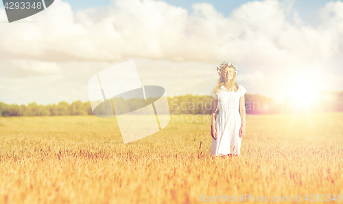 Image of happy young woman in flower wreath on cereal field