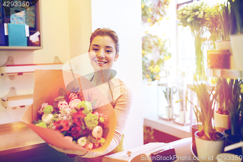 Image of smiling florist woman with bunch at flower shop