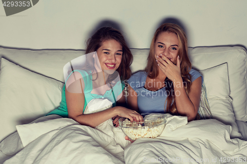 Image of happy friends with popcorn and watching tv at home