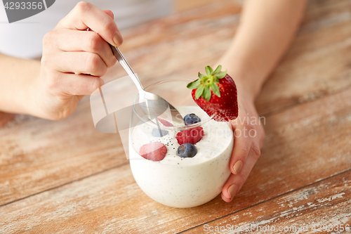 Image of woman hands with yogurt and berries on table