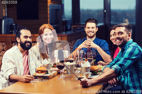 Image of friends taking selfie by smartphone at restaurant