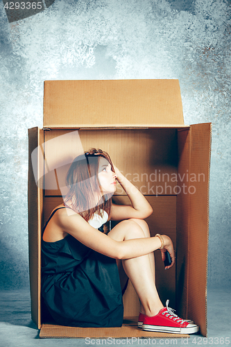 Image of Introvert concept. Woman sitting inside box and working with phone