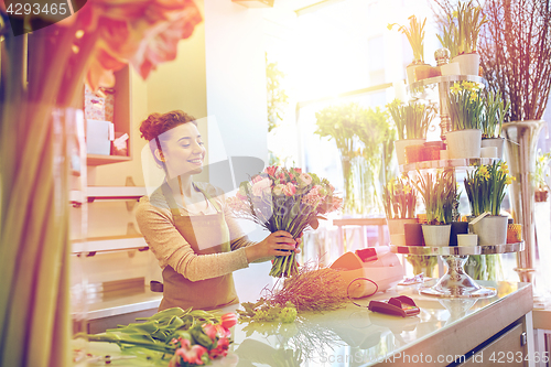 Image of smiling florist woman making bunch at flower shop
