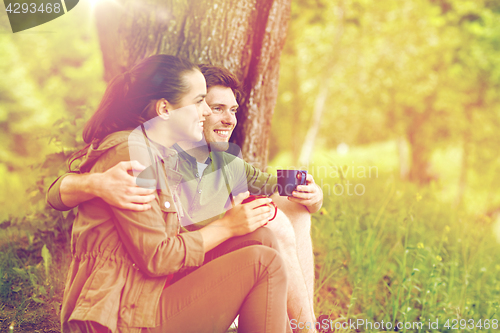 Image of happy couple with cups drinking tea in nature