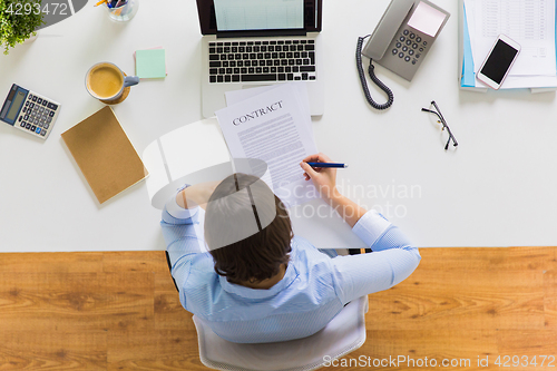 Image of businesswoman signing contract document at office