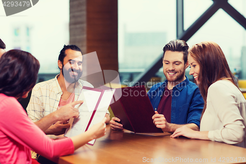 Image of smiling friends discussing menu at restaurant