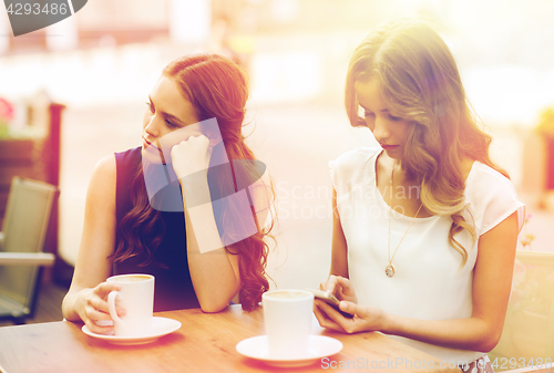 Image of women with smartphones and coffee at outdoor cafe