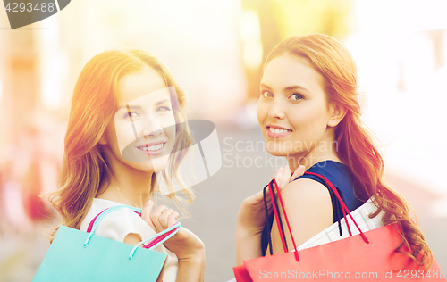 Image of happy women with shopping bags walking in city 