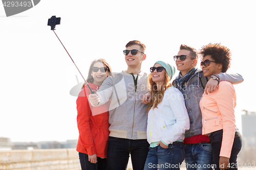 Image of happy friends taking selfie by smartphone outdoors