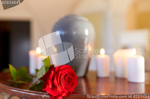 Image of red rose and cremation urn with burning candles