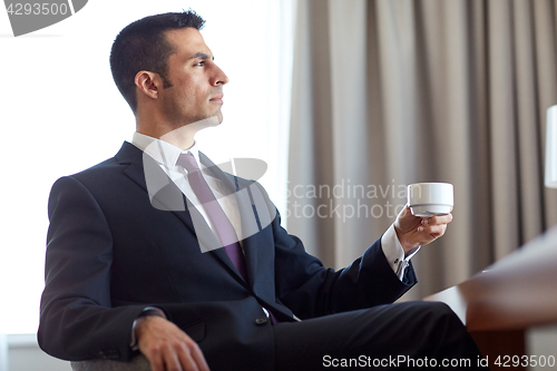 Image of businessman drinking coffee at hotel room