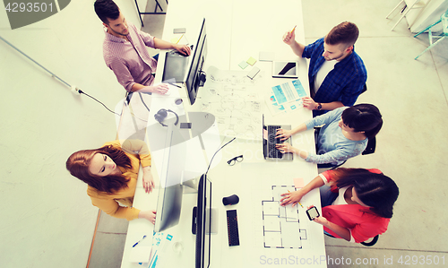 Image of creative team with computers, blueprint at office