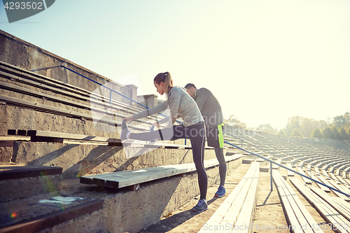 Image of couple stretching leg on stands of stadium