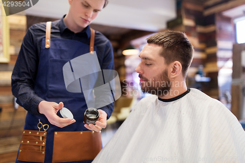 Image of barber showing hair styling wax to male customer