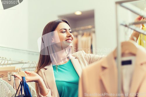 Image of happy young woman choosing clothes in mall