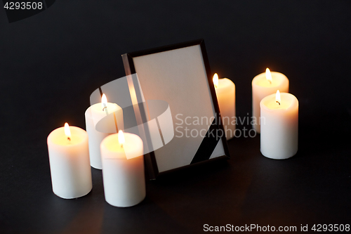 Image of black ribbon on photo frame and candles at funeral