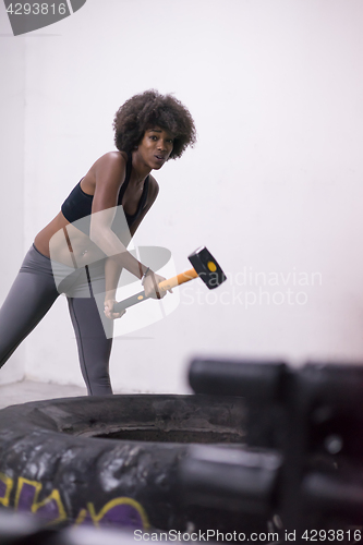 Image of black woman workout with hammer and tractor tire