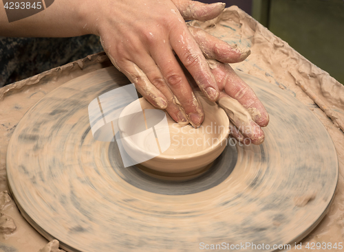 Image of Woman hands in clay at process of making clay bowl on pottery wh