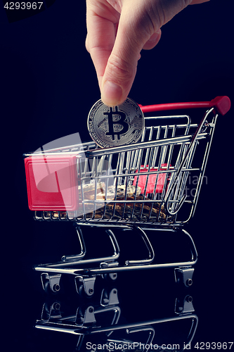 Image of hand throws a bitcoin into trolley.