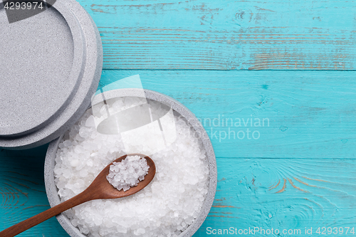 Image of Sea salt in an stone bowl with small wooden spoon on a blue wooden table