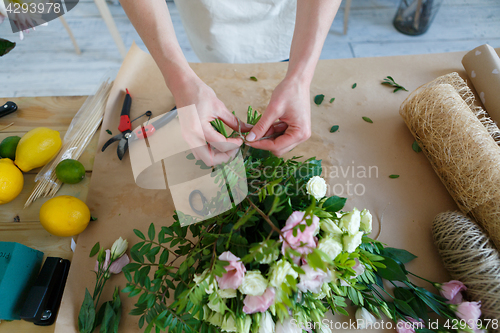 Image of Florist makes bouquet on table