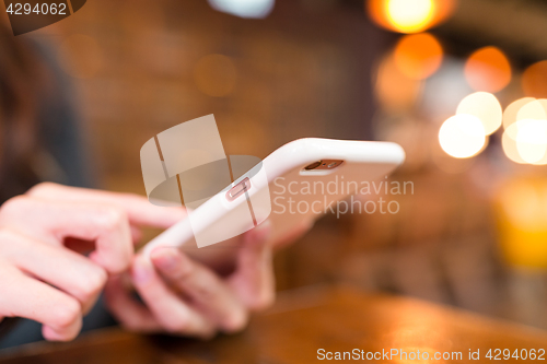 Image of Woman sending sms on cellphone in restaurant