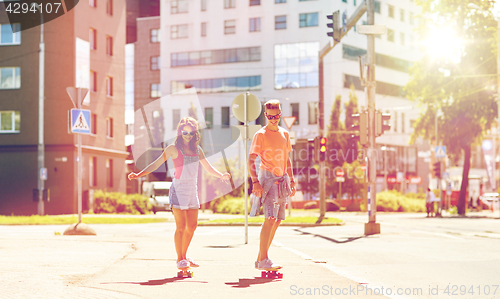 Image of teenage couple riding skateboards on city street