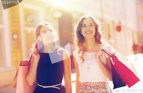 Image of happy women with shopping bags walking in city 