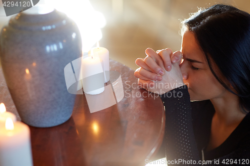 Image of sad woman with funerary urn praying at church