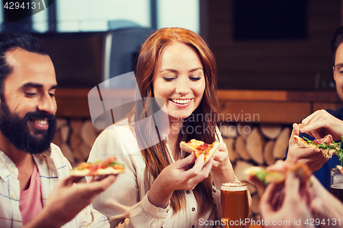 Image of friends eating pizza with beer at restaurant