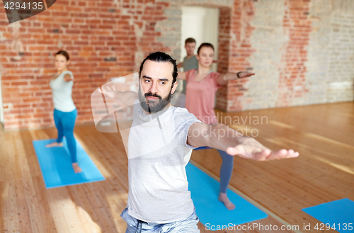 Image of group of people doing yoga warrior pose at studio